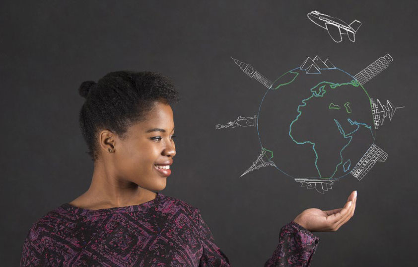 A woman smiles while holding out her hand, appearing to support a chalk drawing of a globe with famous landmarks and an airplane on a blackboard background.