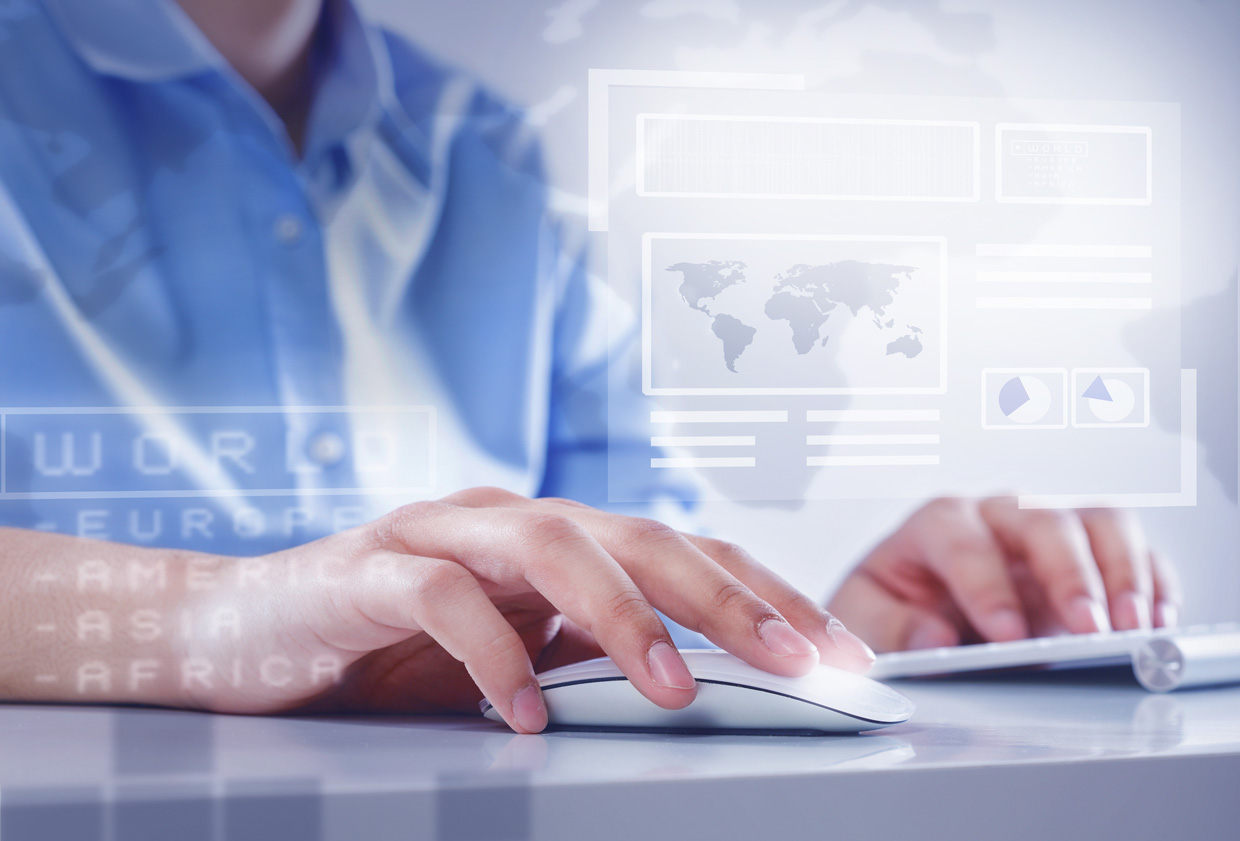 A person using a computer mouse and keyboard with digital interface graphics, including world maps and data charts, overlaid in the foreground, suggesting global data analysis or technology use.
